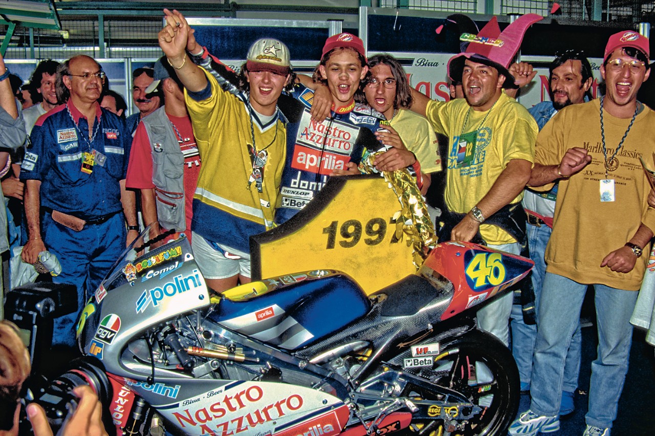 <div class='descrGalleryTitle'>1997 - IL PRIMO IRIDE</div><div class='descrGalleryText'><p>Alla seconda stagione nel Motomondiale, Rossi e l’Aprilia RS 125 diventano una coppia invincibile: in 15 gare arrivano ben 11 vittorie. Arriva il primo titolo mondiale.&nbsp;</p>
</div>